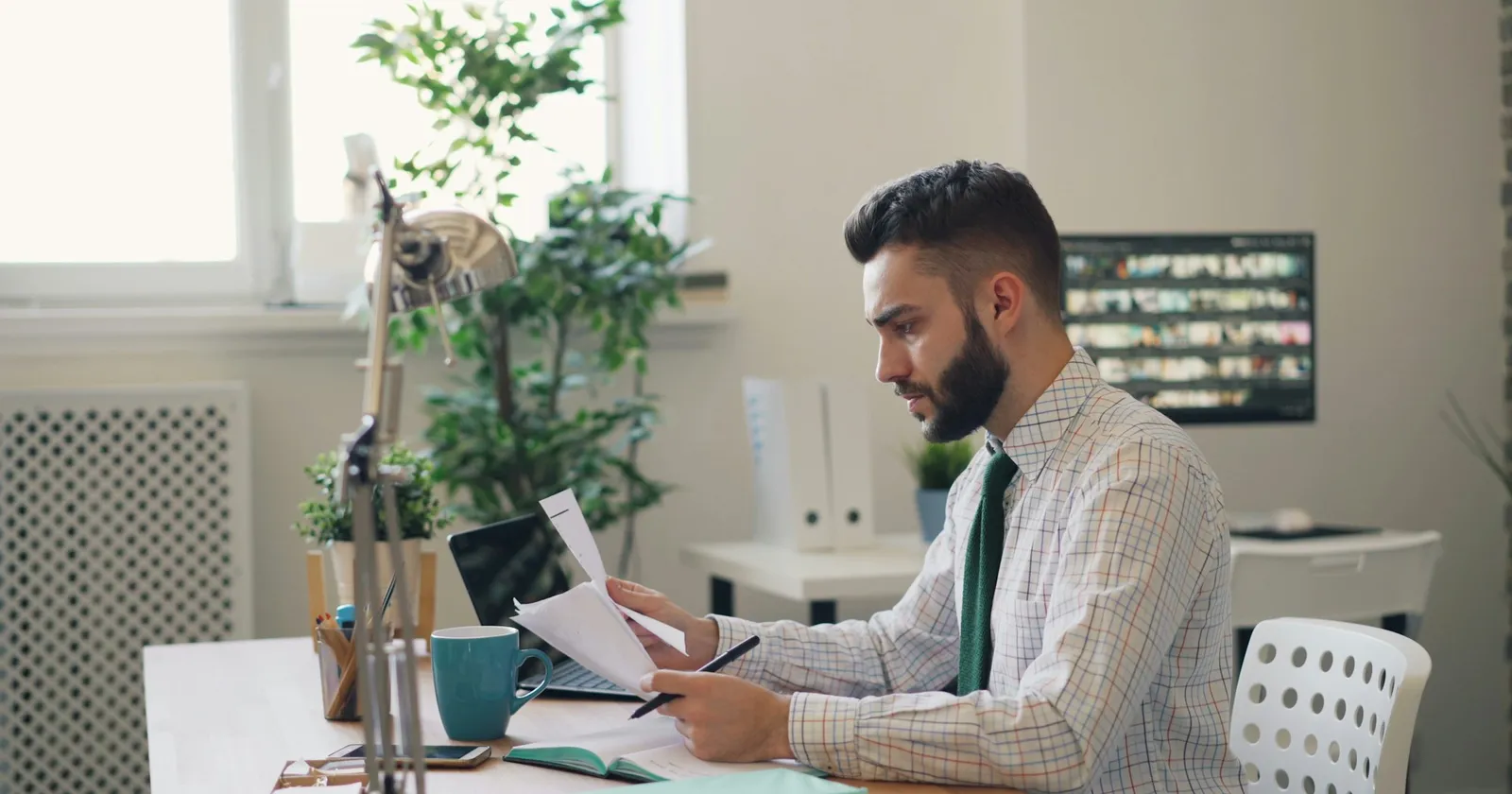 Pria berkemeja membaca surat dengan serius di meja kantor