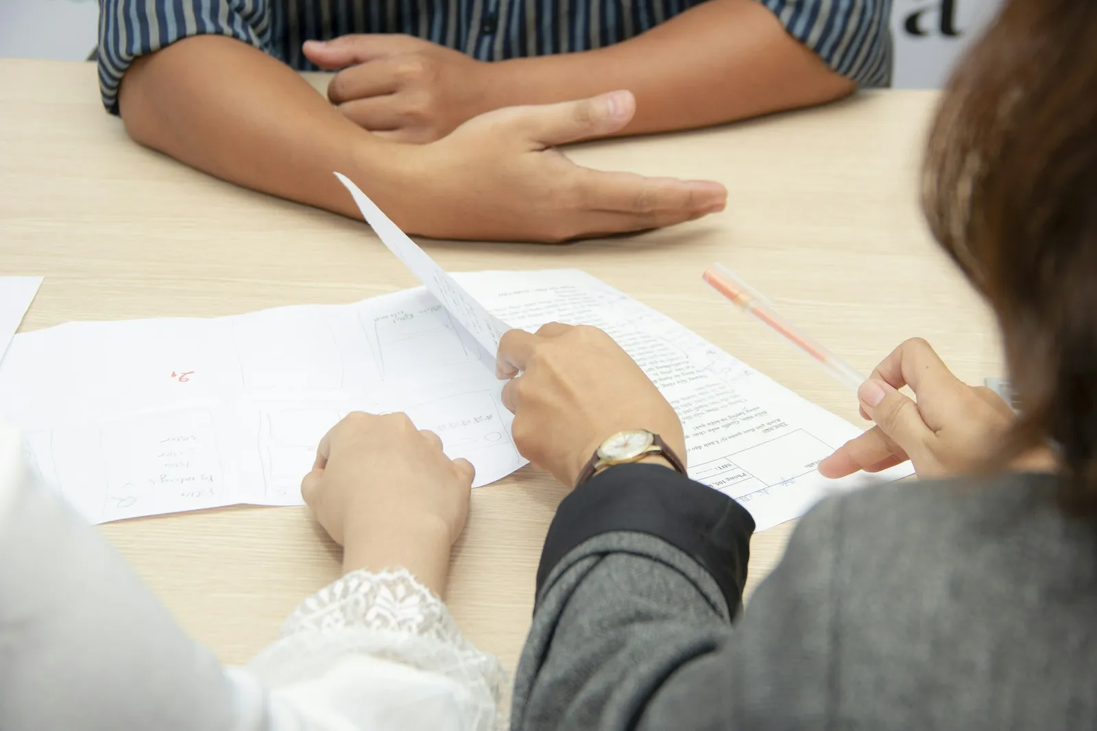 Dua orang membahas dokumen tercetak di meja rapat