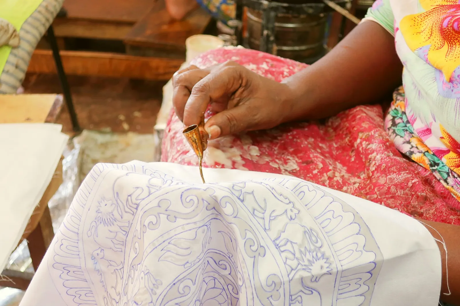 Perajin batik menorehkan malam pada kain dengan canting